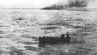 Al fondo el Ferrandiz hundiéndose, y el bote del Canarias de regreso con los rescatados de la dotación.