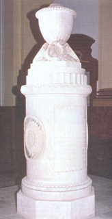  Fotografía del mausoleo con sus restos, una columna cilíndrica.